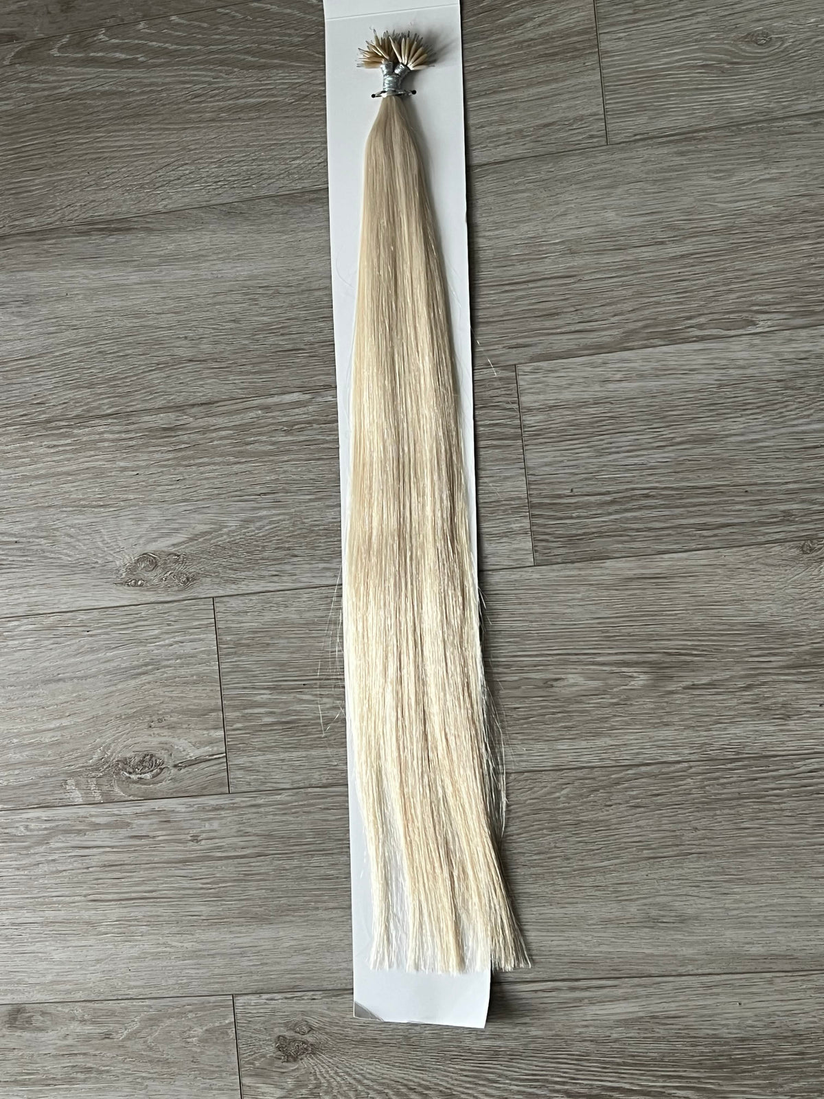 Full-length straight platinum blonde #1001 nano bead hair strand with nano ring, displayed on white card