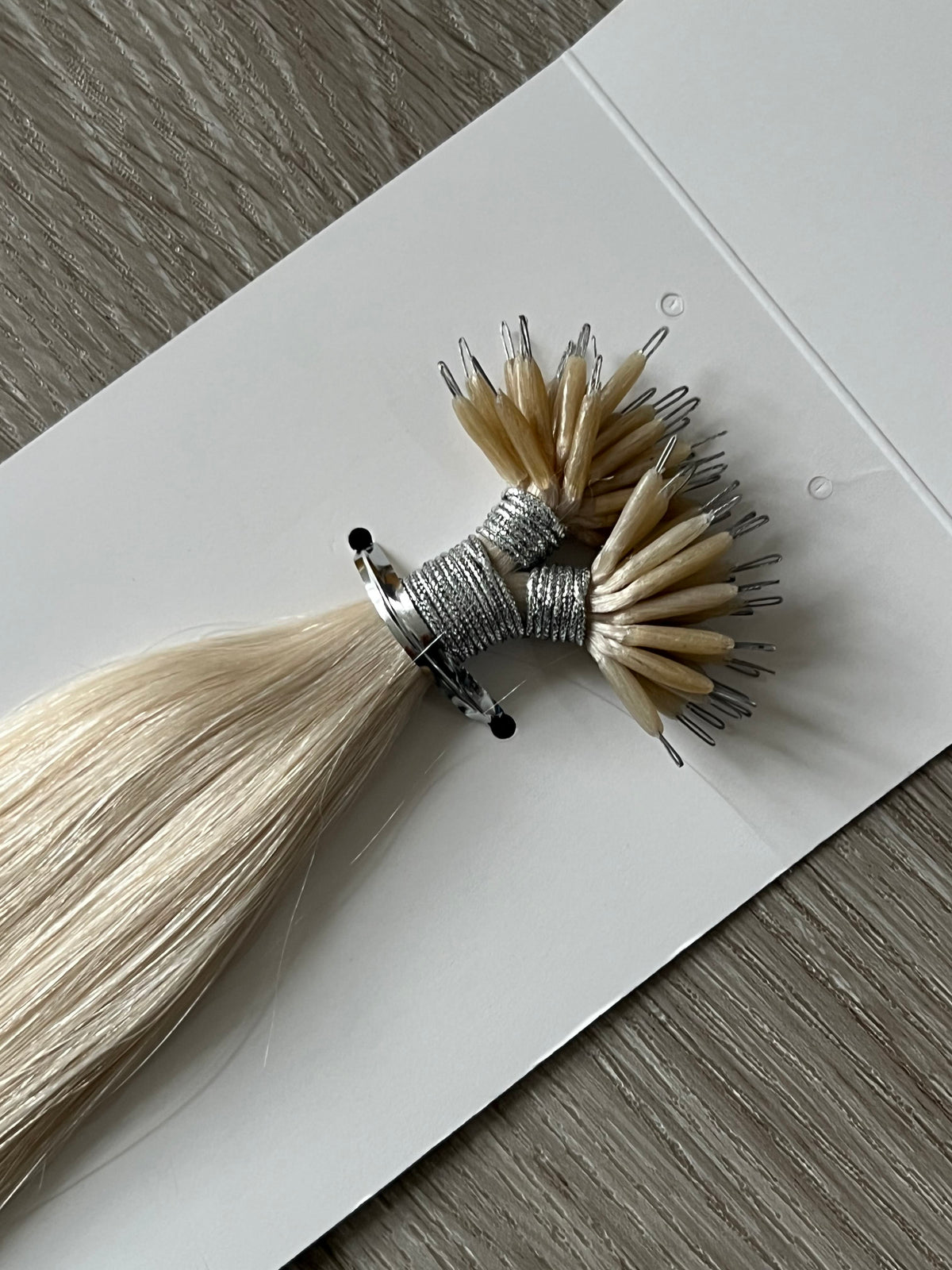 Nano rings close-up, platinum blonde #1001 nano bead hair extensions, tied bundle on white paper